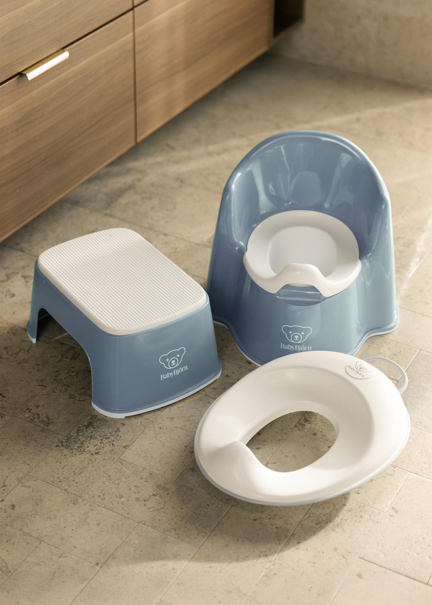 Blue children's potty chair, step stool, and toilet seat reducer on a tiled bathroom floor.